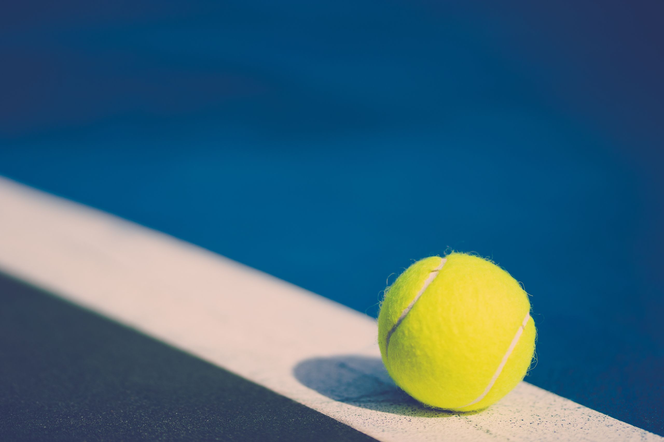 one new tennis ball on white diagonal line in blue hard court wi